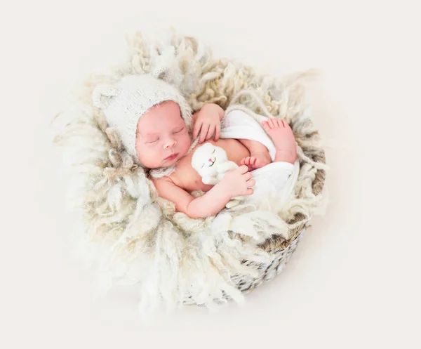 Küçük bir oyuncak ile sepette uyuyan yeni doğan bebek — Stok fotoğraf