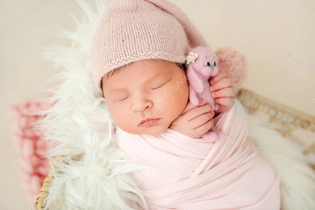 newborn baby sleeping with a small toy