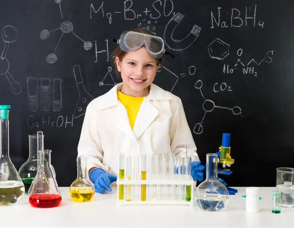 Beyaz cüppeli kız, sıvılarla deney yapıyor.
