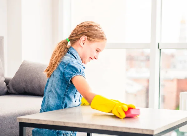 Klein meisje schoonmaken houten tafel — Stockfoto