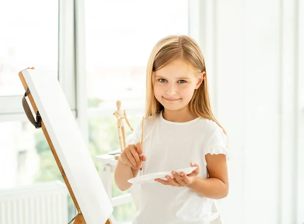 Söt liten flicka målar på duk — Stockfoto