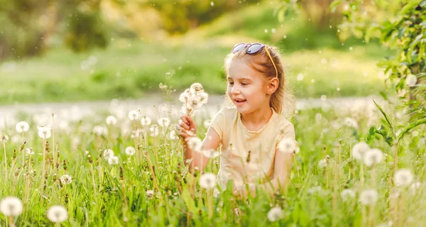 Roztomilá dívka si hraje s pampelišky — Stock fotografie