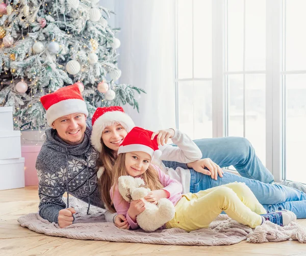 Sonriente familia en santa sombreros acostados juntos —  Fotos de Stock
