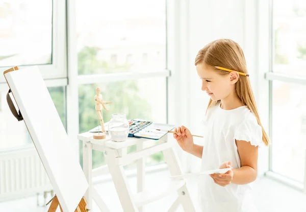 Menina criança pintando imagens diferentes no cavalete — Fotografia de Stock