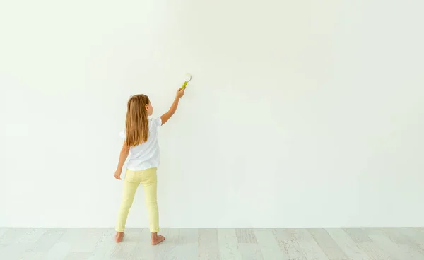 Menina pintura na parede branca dentro de casa — Fotografia de Stock