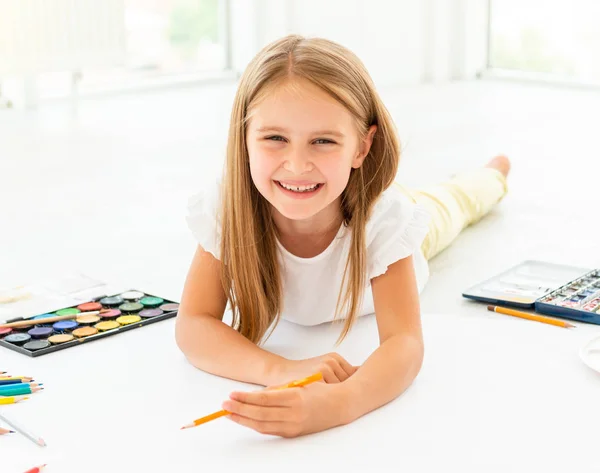 Menina desenha deitado no chãopequena menina alegre desenha deitado no chão — Fotografia de Stock