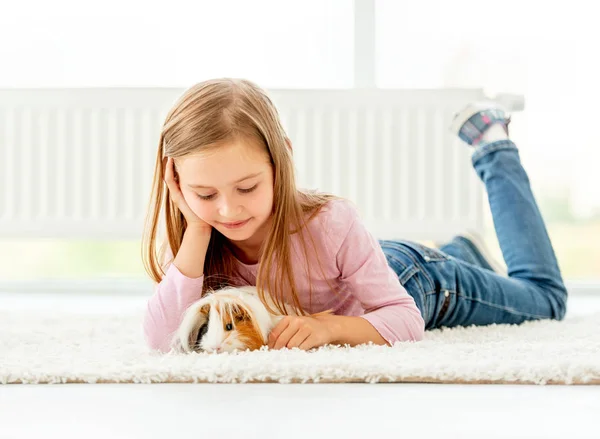 Girl holding guinea pig on the floor — Stock Photo, Image