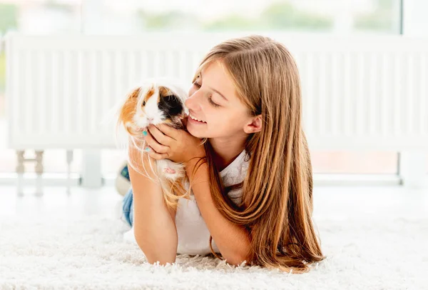 Young teen girl holding guinea pig on the floor — Stock Photo, Image