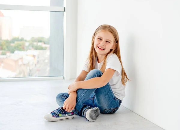 Leende liten flicka sitter på golvet — Stockfoto