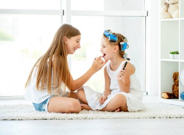 Bir çocuk kız kardeş makyaj koyarak diğer yardım