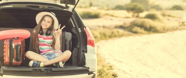 Schattig meisje in de kofferbak van een auto met koffers — Stockfoto