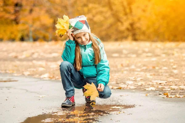 Söt liten tjej huk med blad i hand — Stockfoto