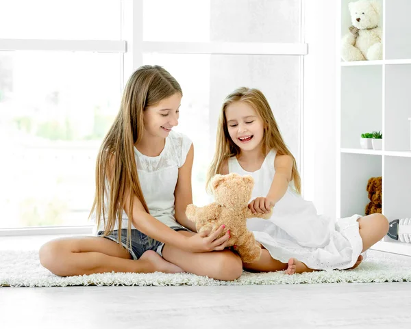 Sisters playing with teddy bear toy — Stock Photo, Image