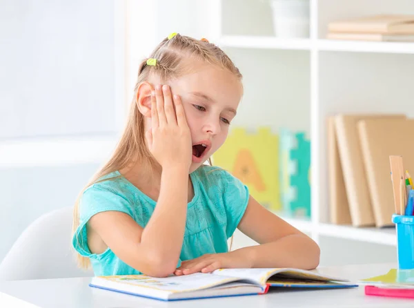 Ragazza sbadigliando davanti al libro aperto — Foto Stock