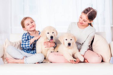 Gülümseyen kız kardeşler köpek yavrularıyla oturuyor