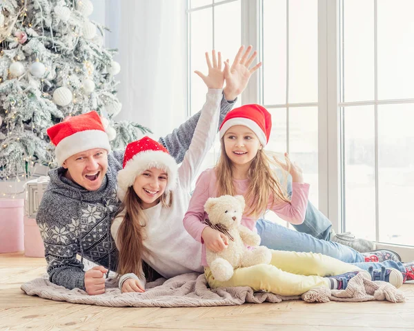 Usmívající se rodina v Santa špicích ležících pohromadě — Stock fotografie