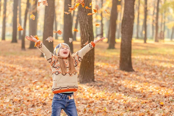 Маленька дівчинка викидає листя — стокове фото