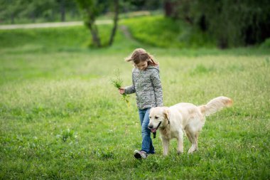 Çiçeklerle gezen küçük tatlı kız.