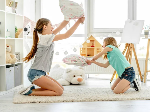 Meninas sorridentes lutando com travesseiros — Fotografia de Stock