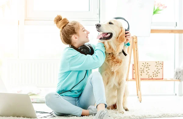 Meisje zet koptelefoon op schattige hond — Stockfoto