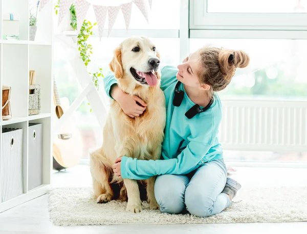 Söt flicka omfamnar söt hund hemma — Stockfoto