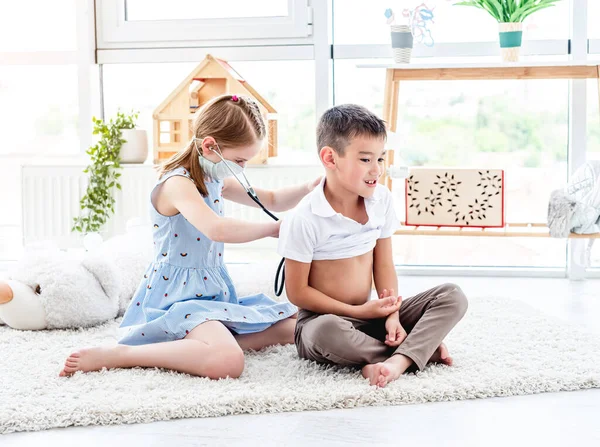 Menina com fonendoscópio menino escuta — Fotografia de Stock
