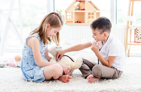 Niños jugando doctor con osito de peluche —  Fotos de Stock