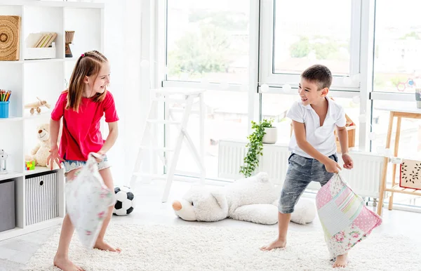 Riendo niños divirtiéndose mientras almohada lucha —  Fotos de Stock