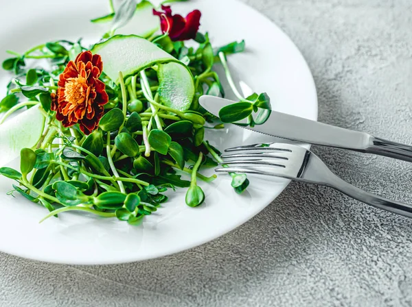 Gabel und Messer auf Teller mit Salat — Stockfoto