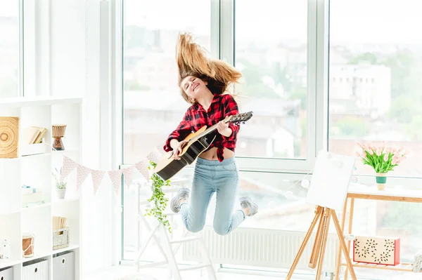 Молодая девушка с гитарой в прыжке — стоковое фото
