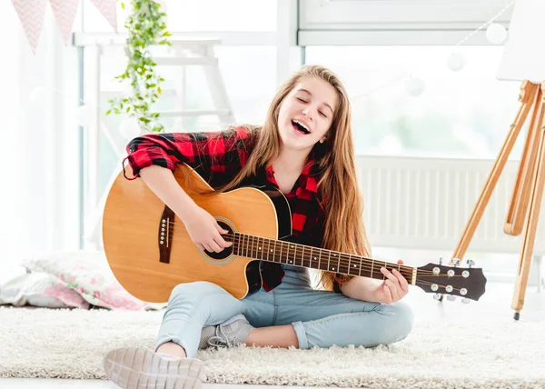 Bella ragazza che suona la chitarra seduta sul pavimento — Foto Stock