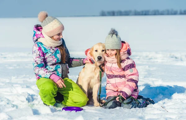 Nővérek ölelés kutya a téli napon — Stock Fotó