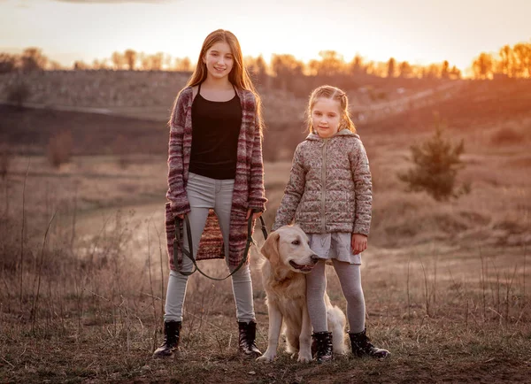 Söta systrar kramar hund utomhus — Stockfoto