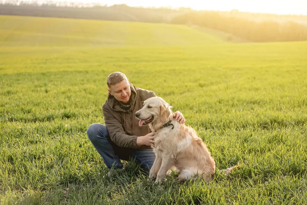 Människan gosande hund på fältet — Stockfoto