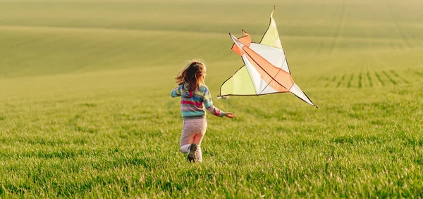 Klein meisje met vlieger bij zonsondergang — Stockfoto
