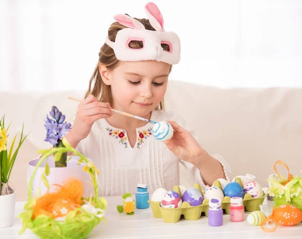 Girl coloring eggs in mask — Stock Photo, Image