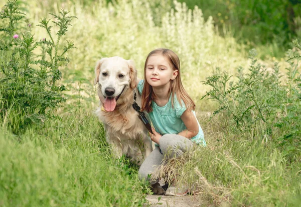 Gadis kecil dengan golden retriever di padang rumput — Stok Foto