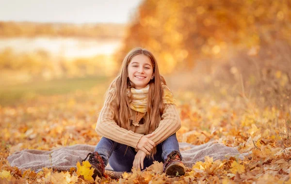 Niña sentada en hojas amarillas — Foto de Stock