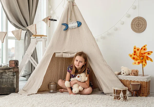 Menina abraçando pelúcia de pelúcia em wigwam — Fotografia de Stock