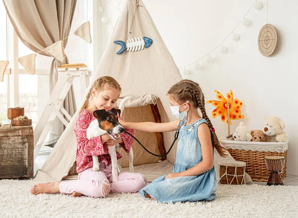 Маленькі дівчата з фонендоскопом слухають собаку — стокове фото