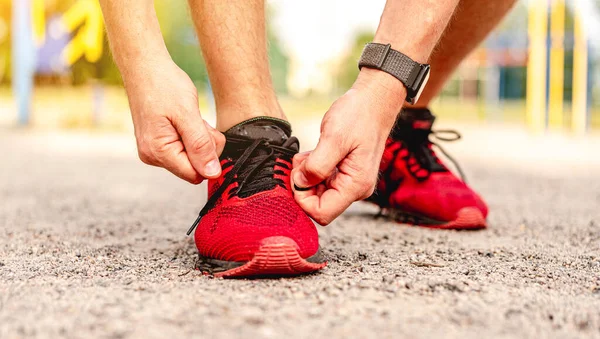 Uomo allacciatura lacci su scarpe da ginnastica rosse — Foto Stock