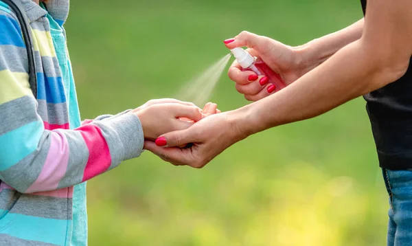 Kvinnan sprider rengöringsmedel på tjejhänder — Stockfoto