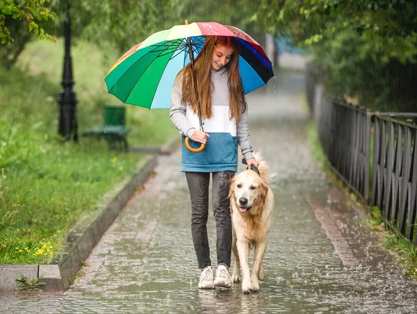 Jong meisje wandelen onder regen met hond — Stockfoto