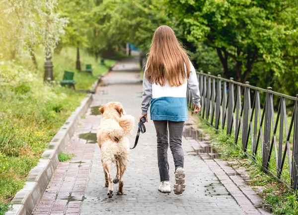 Flicka rastande hund längs våt gränd — Stockfoto