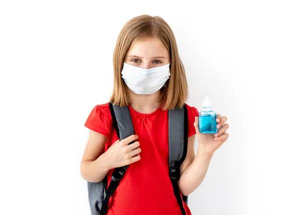 Μαθήτρια με ιατρική μάσκα που κρατάει απολυμαντικό. — Φωτογραφία Αρχείου