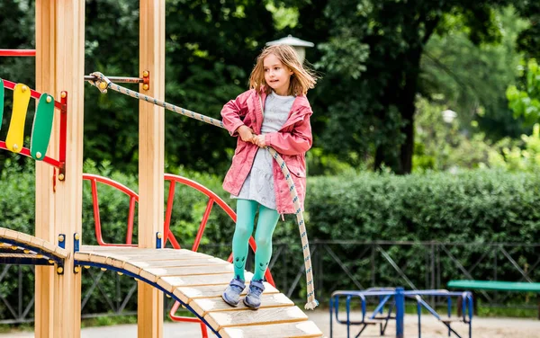 Little girl climbing rope on playground — Stock Photo, Image