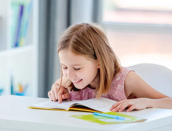 Little girl reading book in classroom — Stock Photo, Image
