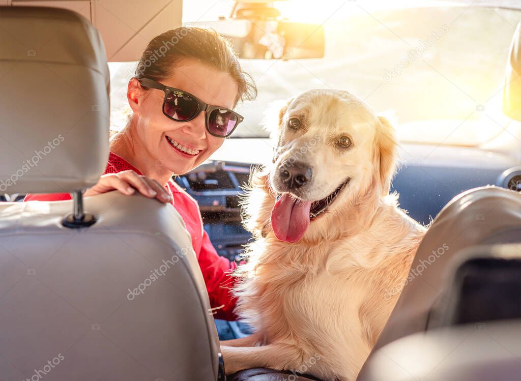 Woman with golden retriever on car seats