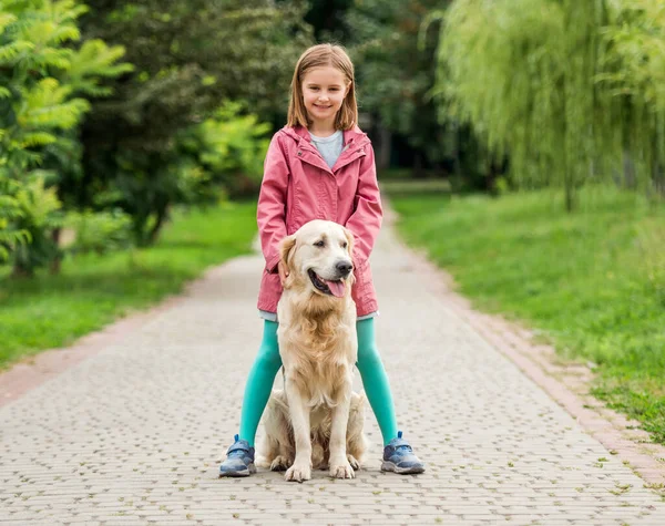 Klein meisje staand met hond tussen de voeten — Stockfoto