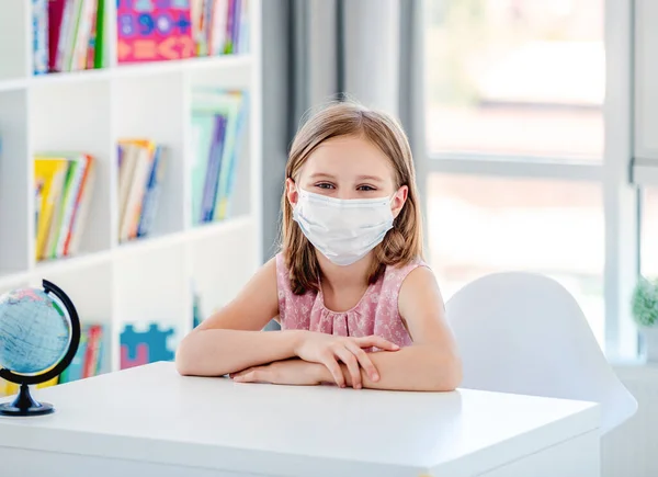 Schulmädchen in Maske sitzt auf Unterricht — Stockfoto